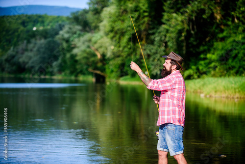 What a fish. mature bearded man with fish on rod. big game fishing. relax on nature. hipster fishing with spoon-bait. successful fisherman in lake water. fly fish hobby. Summer activity