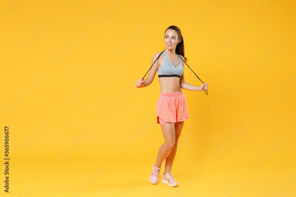 Full length portrait of beautiful young fitness woman girl in sportswear working out isolated on yellow wall background studio portrait. Workout sport motivation lifestyle concept. Hold skipping rope. Full length portrait of beautiful young fitness woman girl in sportswear working out isolated on yellow wall background studio portrait. Workout sport motivation lifestyle concept. Hold skipping rope.