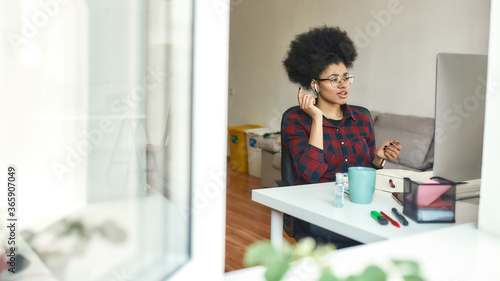 E-learning. Young afro american female student wearing wireless headphones studying foreign language online at home. View from the street through window