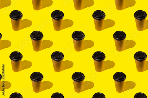 Take out coffee in brown thermo cup on bright yellow background. Coffee cup on yellow abstract pattern photo