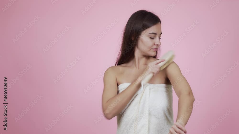 Portrait of woman doing body massage with brush isolated on pink background Portrait of woman doing body massage with brush isolated on pink background