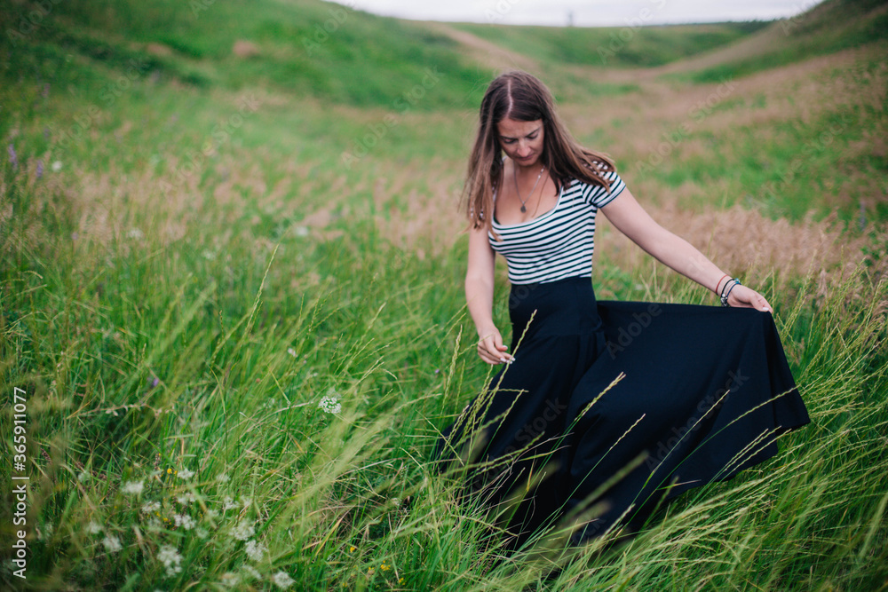 Beautiful girl in a black long skirt and striped T-shirt walks in green hole Beautiful girl in a black long skirt and striped T-shirt walks in green hole