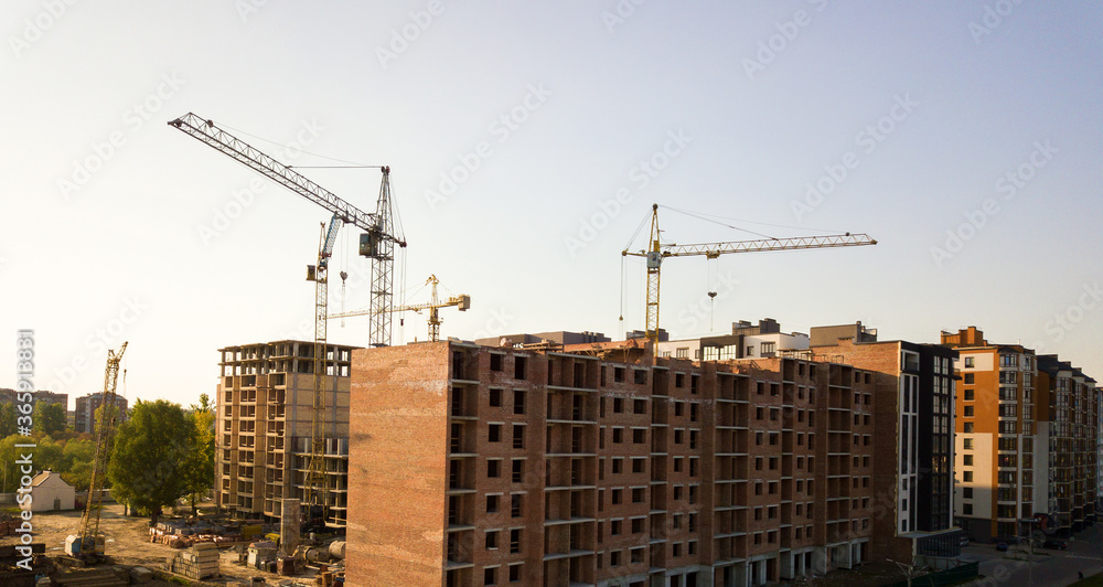 High multi storey residential apartment buildings under construction. Concrete and brick framing of high rise housing. Real estate development in urban area.