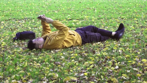 Alone men with yellow jacket using smartphone in the park of the fall. photo