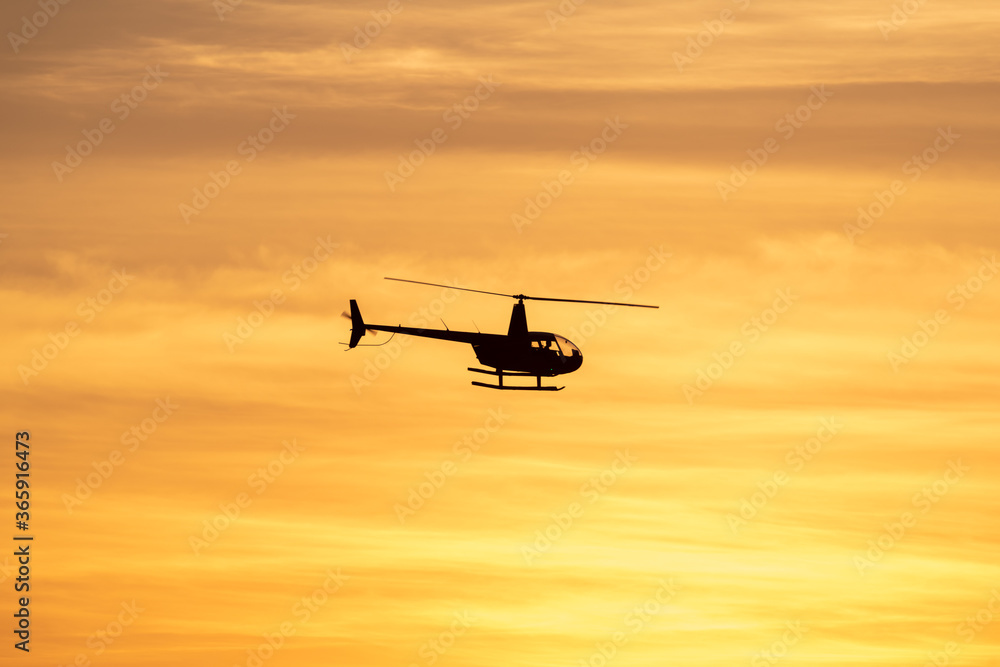 Helicopter silhouette with vibrant sunset sky with clouds Helicopter silhouette with vibrant sunset sky with clouds