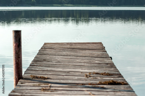 Wooden pier on the background of a beautiful lake summer dawn landscape. Copy space.