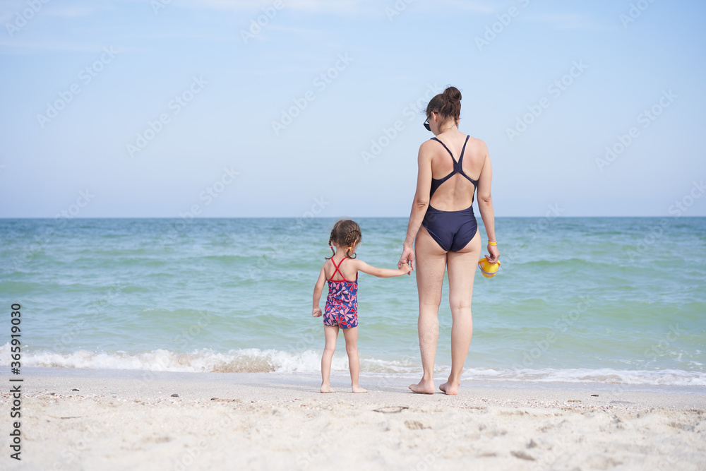 Mother daughter beach together rear view Unrecognizable caucasian woman little girl swimwear standing seaside back.