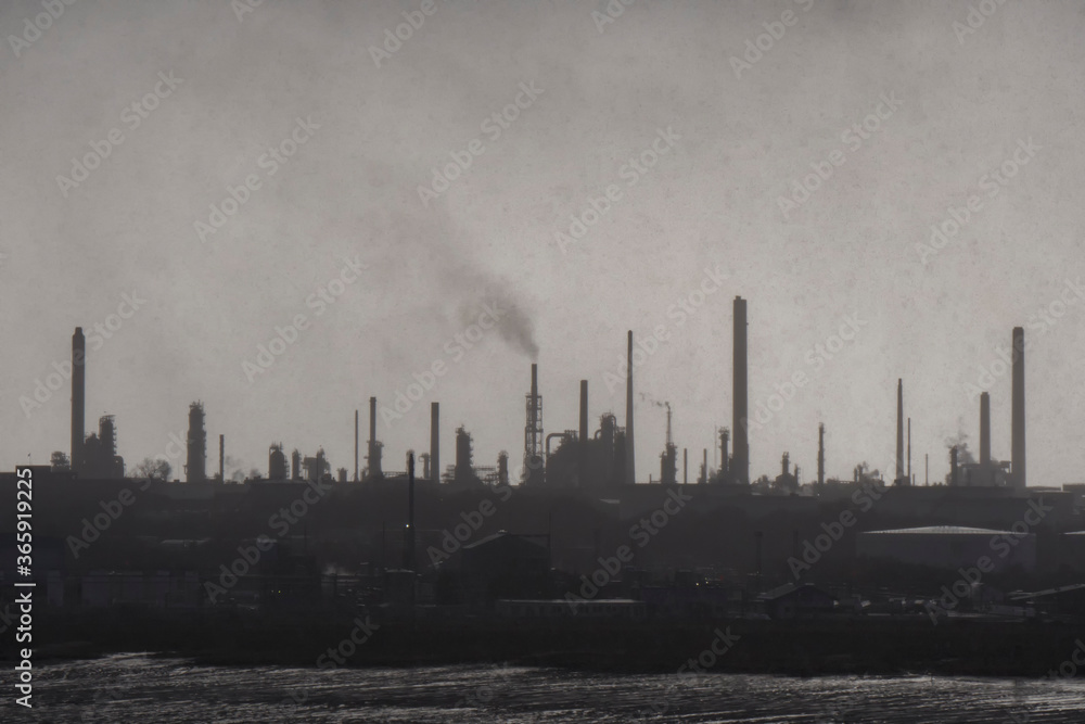 oil refinery by the sea in winter in gray tones in the early morning