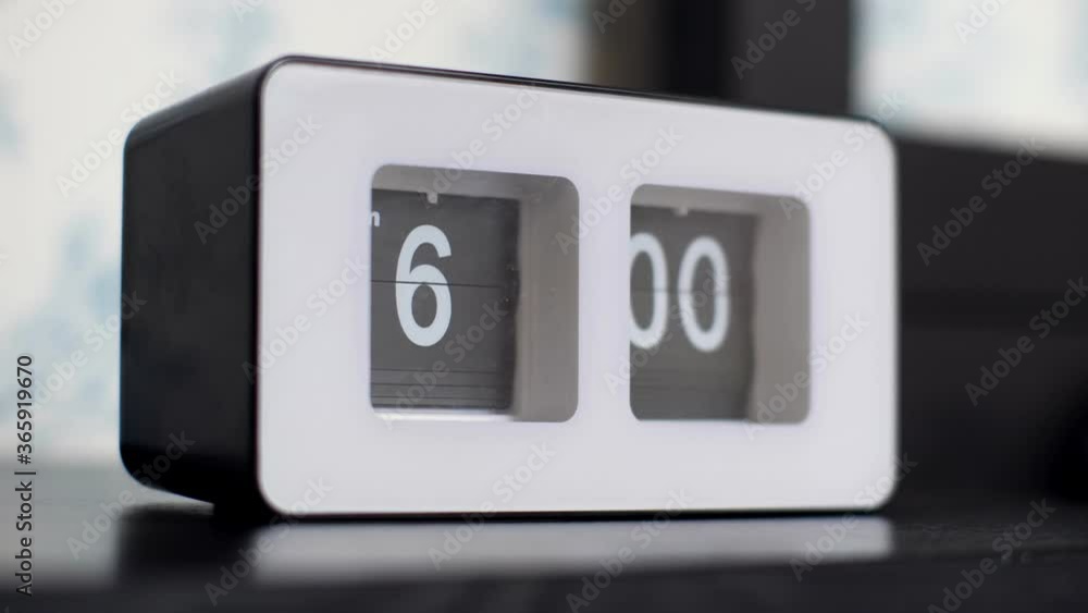 flip clock with white numbers on black panel shows 6 am