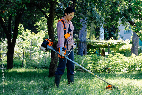 Woman mowing the grass in garden. Lawn care concept