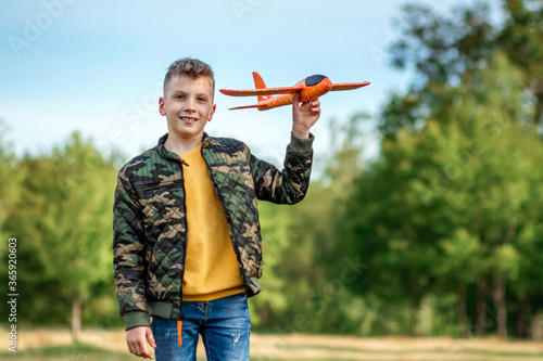 The boy launches a toy airplane against the backdrop of greenery. The concept of dreams, choice of profession, pilot, childhood. Copy space.