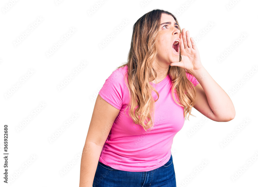 Young caucasian woman wearing sportswear shouting and screaming loud to side with hand on mouth. communication concept. Young caucasian woman wearing sportswear shouting and screaming loud to side with hand on mouth. communication concept.