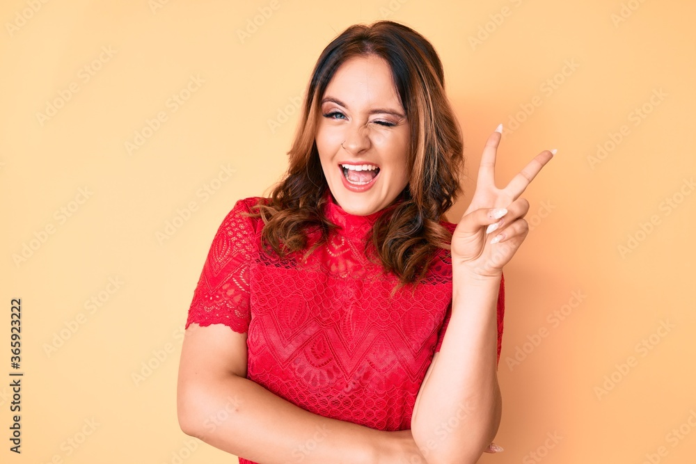Young beautiful caucasian woman wearing casual clothes smiling with happy face winking at the camera doing victory sign. number two. Young beautiful caucasian woman wearing casual clothes smiling with happy face winking at the camera doing victory sign. number two.