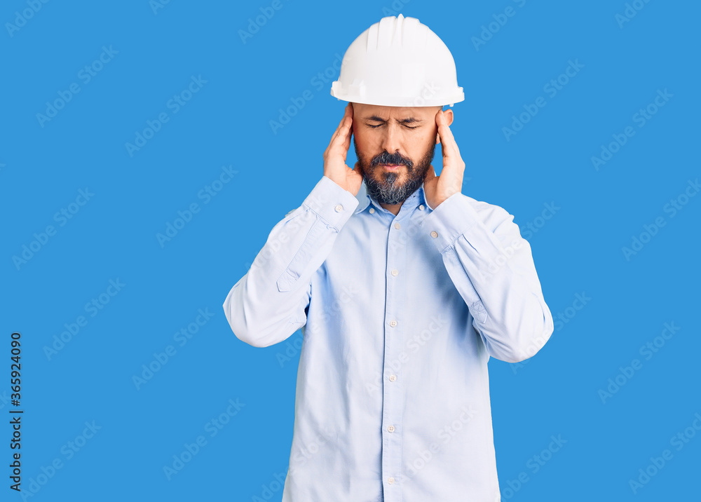 Young handsome man wearing architect hardhat with hand on head for pain in head because stress. suffering migraine. Young handsome man wearing architect hardhat with hand on head for pain in head because stress. suffering migraine.