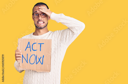 Photo Young handsome man holding act now banner stressed and frustrated with hand on h