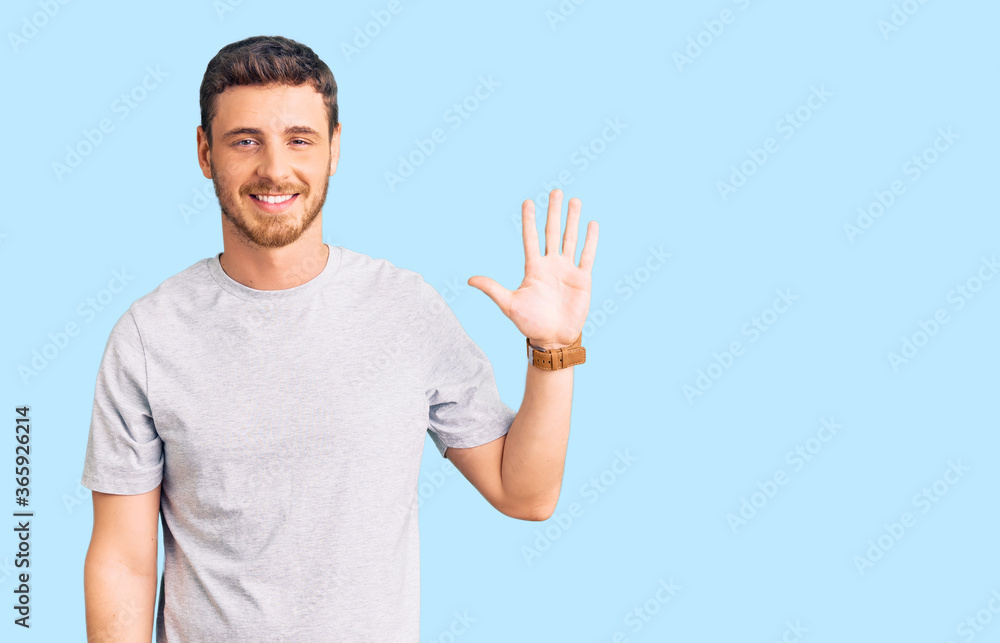 Handsome young man with bear wearing casual tshirt showing and pointing up with fingers number five while smiling confident and happy. Handsome young man with bear wearing casual tshirt showing and pointing up with fingers number five while smiling confident and happy.