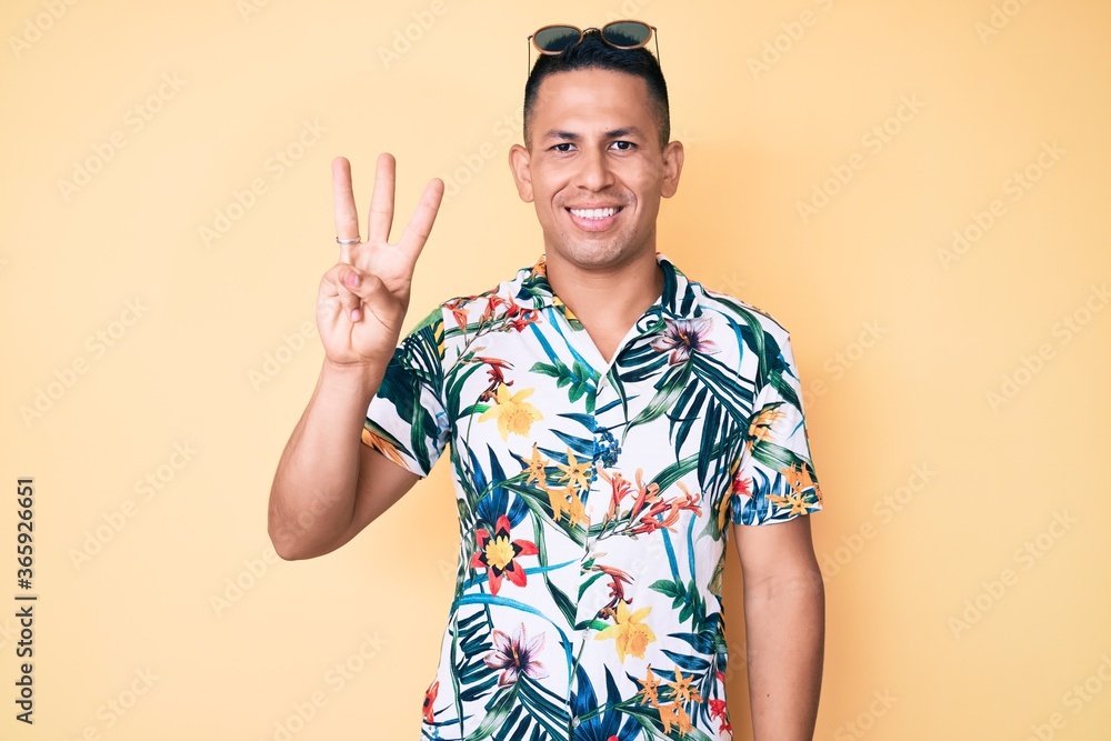 Young handsome latin man wearing summer clothes showing and pointing up with fingers number three while smiling confident and happy. Young handsome latin man wearing summer clothes showing and pointing up with fingers number three while smiling confident and happy.