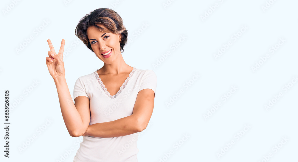 Young beautiful woman wearing casual clothes smiling with happy face winking at the camera doing victory sign. number two. Young beautiful woman wearing casual clothes smiling with happy face winking at the camera doing victory sign. number two.