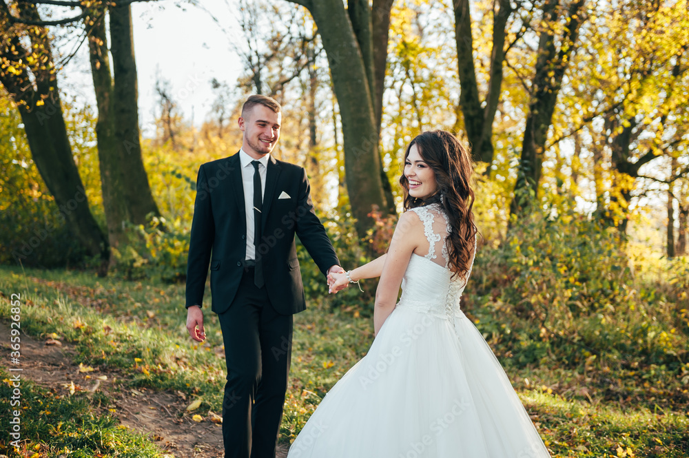 Sunshine portrait of happy bride and groom outdoor in nature location at sunset. Warm summertime. Happy couple with a beautiful bouquet of flowers. Wedding photo. Couple in love. Autumn wedding