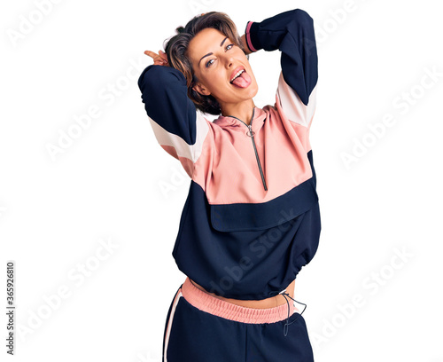 Young beautiful woman wearing sportswear posing funny and crazy with fingers on head as bunny ears, smiling cheerful © Krakenimages.com