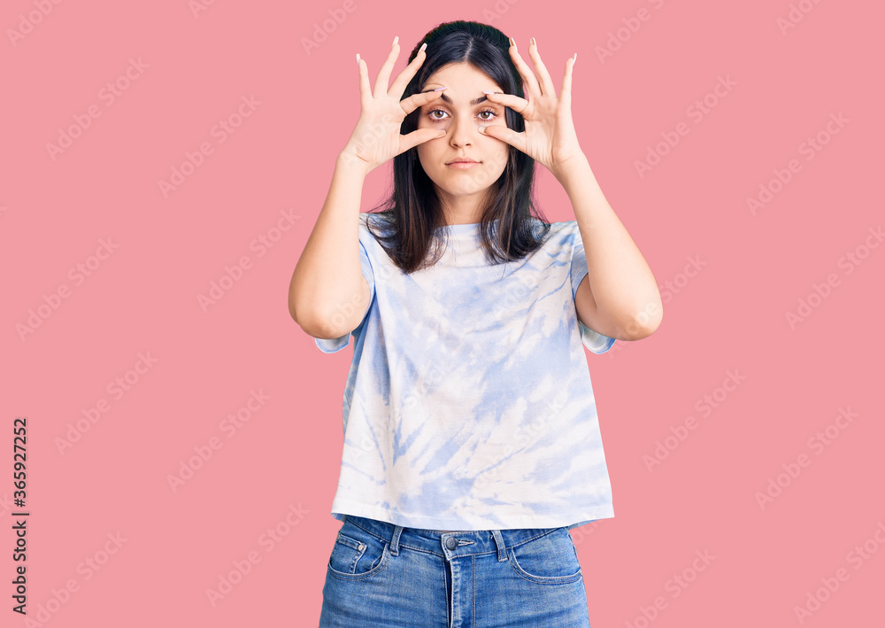 Young beautiful girl wearing casual t shirt trying to open eyes with fingers, sleepy and tired for morning fatigue Young beautiful girl wearing casual t shirt trying to open eyes with fingers, sleepy and tired for morning fatigue