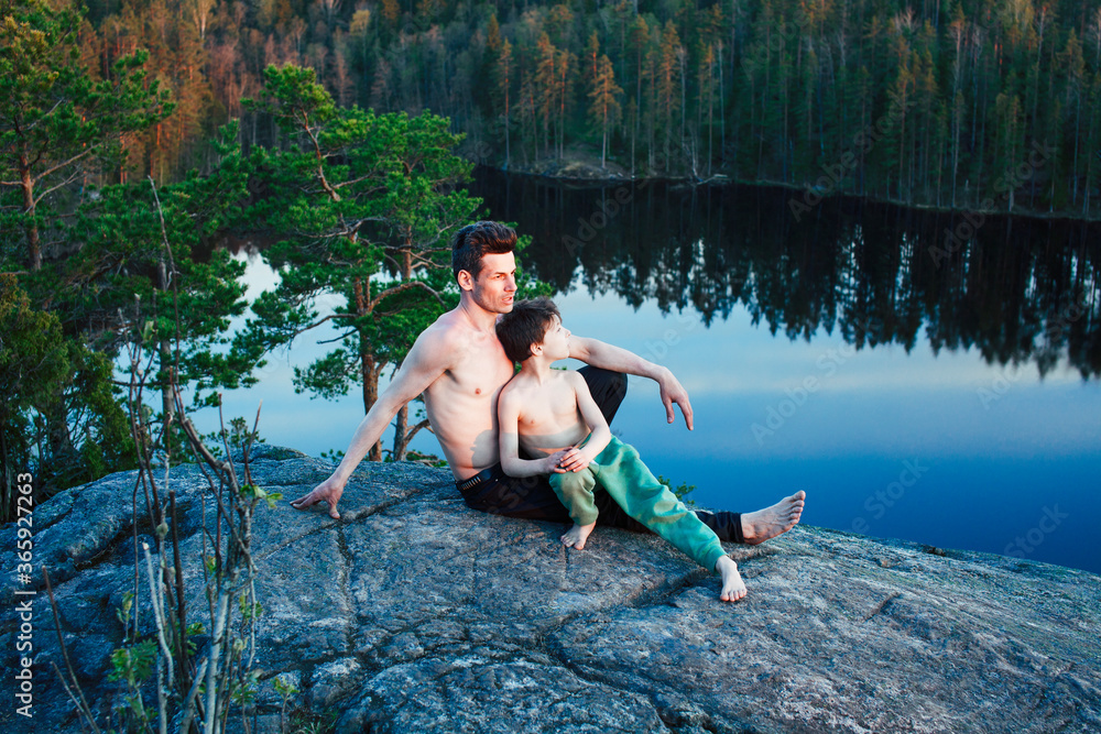 Fototapeta premium middle age man with little cute son doing sport yoga on the top of the mountain together, happy family lifestyle people outdoor, summer wild nature for training
