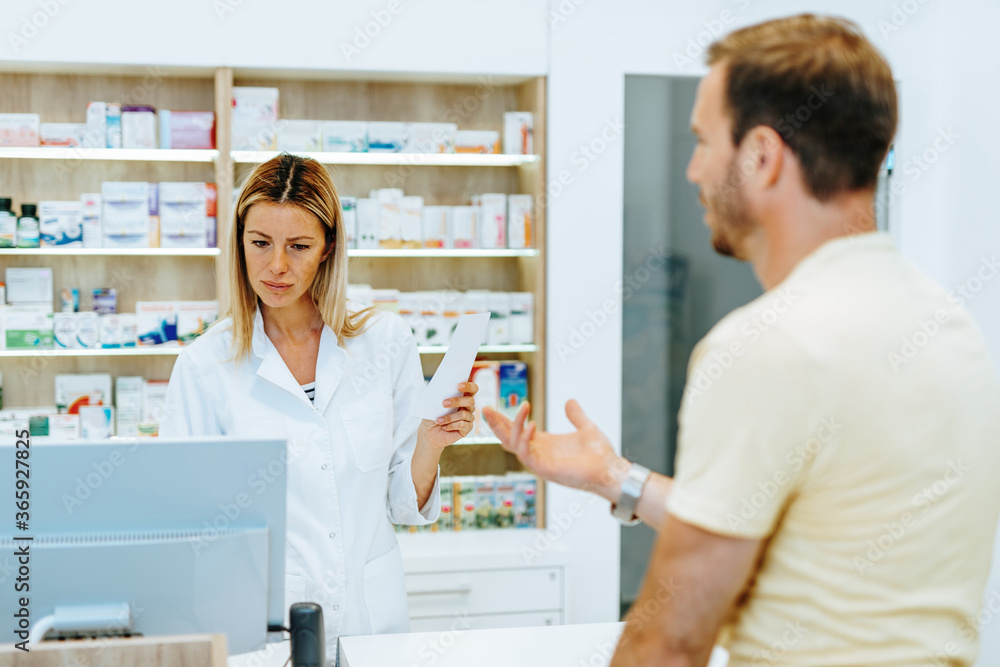 Professional female pharmacist selling pills to customer in modern drugstore.