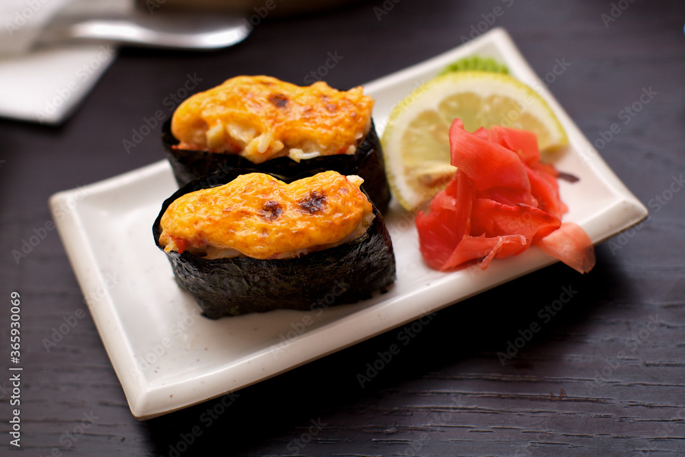 Sushi set, baked minced salmon with cream, set with wasabi, lemon and ginger, on a white plate Sushi set, baked minced salmon with cream, set with wasabi, lemon and ginger, on a white plate