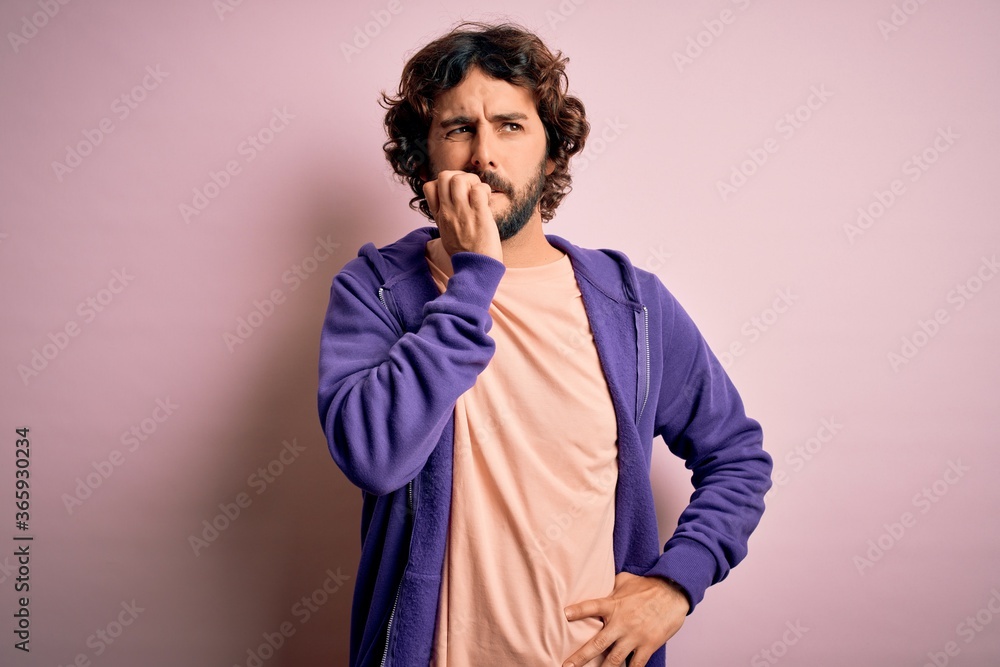 Young handsome sporty man with beard wearing casual sweatshirt over pink background looking stressed and nervous with hands on mouth biting nails. Anxiety problem. Young handsome sporty man with beard wearing casual sweatshirt over pink background looking stressed and nervous with hands on mouth biting nails. Anxiety problem.