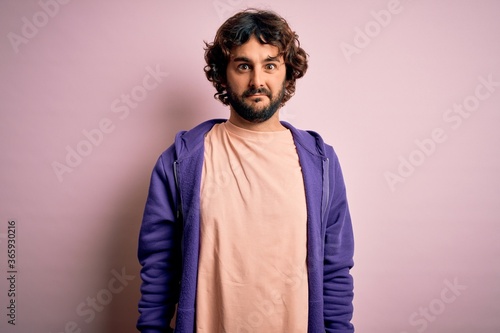 Young handsome sporty man with beard wearing casual sweatshirt over pink background skeptic and nervous  frowning upset because of problem. Negative person.