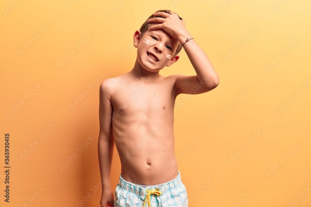 Cute blond kid wearing swimwear stressed and frustrated with hand on head, surprised and angry face