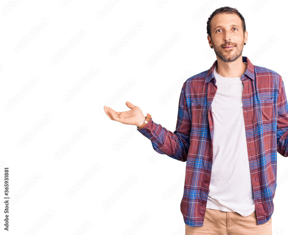 Naklejka premium Young handsome man wearing casual clothes smiling showing both hands open palms, presenting and advertising comparison and balance