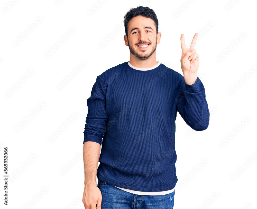 Young hispanic man wearing casual clothes showing and pointing up with fingers number two while smiling confident and happy. Young hispanic man wearing casual clothes showing and pointing up with fingers number two while smiling confident and happy.