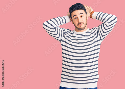 Young hispanic man wearing casual clothes doing bunny ears gesture with hands palms looking cynical and skeptical. easter rabbit concept.