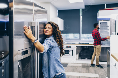 Young couple, satisfied customers choosing fridge in appliances store.