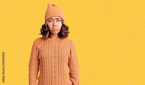 Young beautiful mixed race woman wearing wool sweater and winter hat depressed and worry for distress, crying angry and afraid. sad expression.