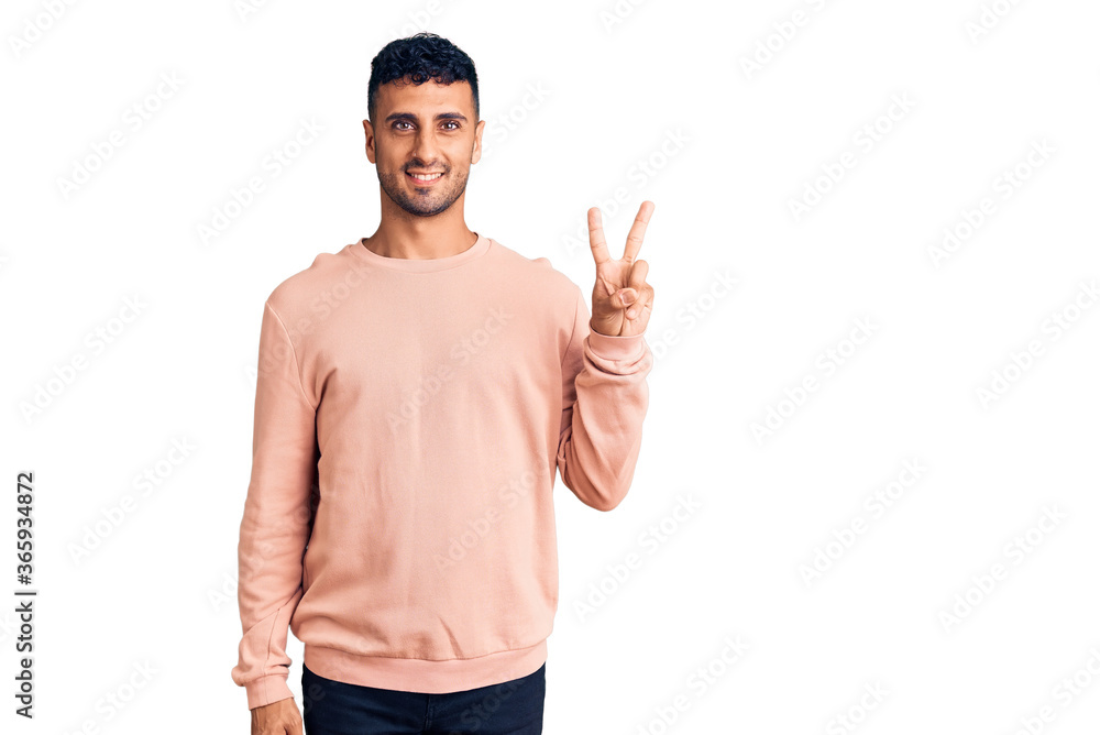 Naklejka premium Young hispanic man wearing casual clothes showing and pointing up with fingers number two while smiling confident and happy.