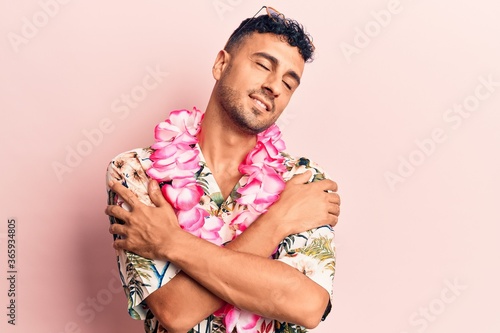 Young hispanic man wearing summer casual clothes hugging oneself happy and positive, smiling confident. self love and self care