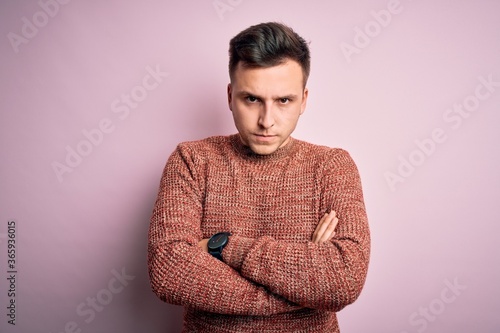 Young handsome caucasian man wearing casual winter sweater over pink isolated background skeptic and nervous, disapproving expression on face with crossed arms. Negative person. © Krakenimages.com