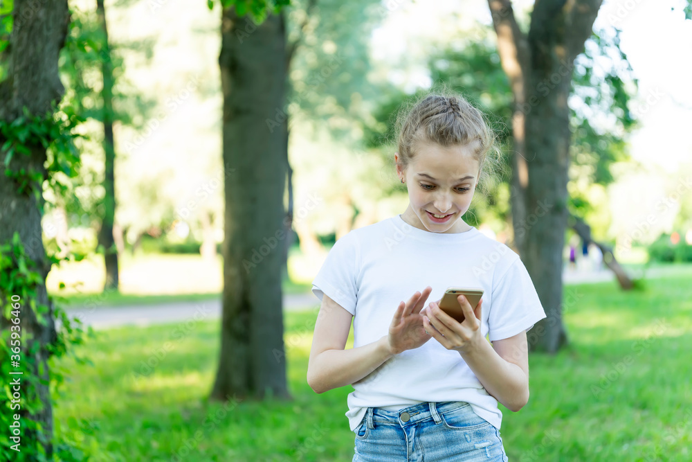 Emotional girl child studies information on the phone. Park, grass, trees. Emotional girl child studies information on the phone. Park, grass, trees.