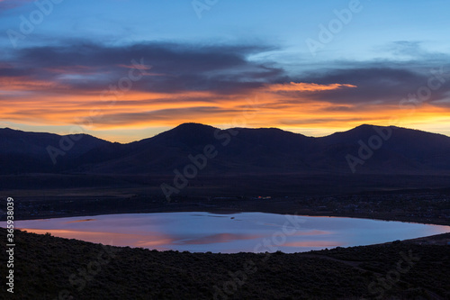 Orange sunset light over a desert mountain with a pond in the foreground © ecummings00
