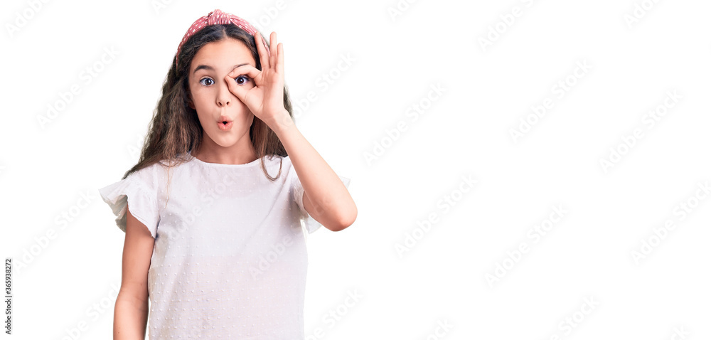 Cute hispanic child girl wearing casual white tshirt doing ok gesture shocked with surprised face, eye looking through fingers. unbelieving expression. Cute hispanic child girl wearing casual white tshirt doing ok gesture shocked with surprised face, eye looking through fingers. unbelieving expression.