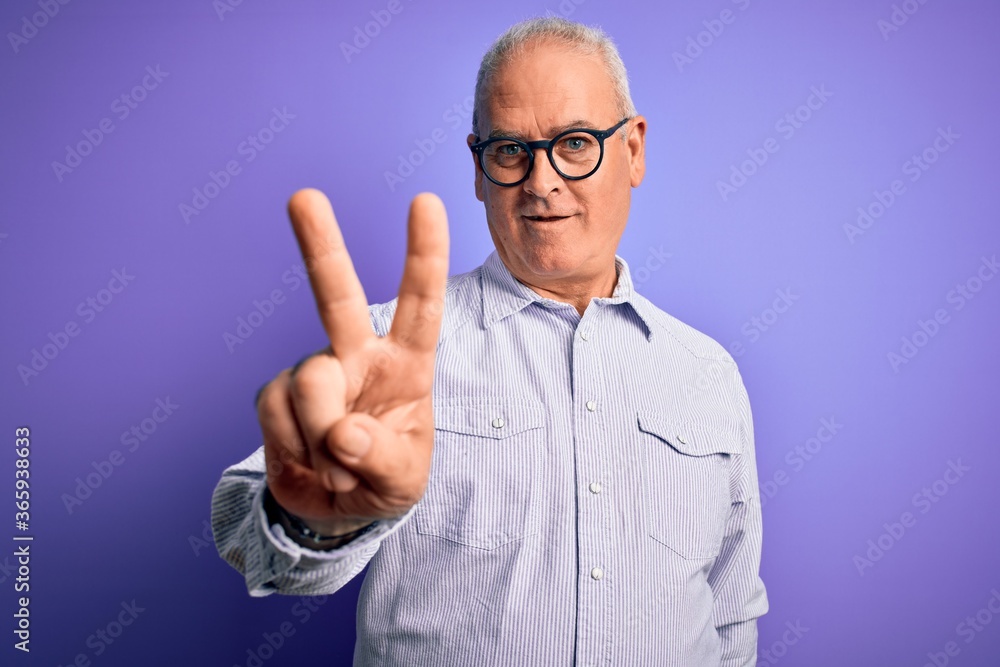 Middle age handsome hoary man wearing striped shirt and glasses over purple background showing and pointing up with fingers number two while smiling confident and happy. Middle age handsome hoary man wearing striped shirt and glasses over purple background showing and pointing up with fingers number two while smiling confident and happy.