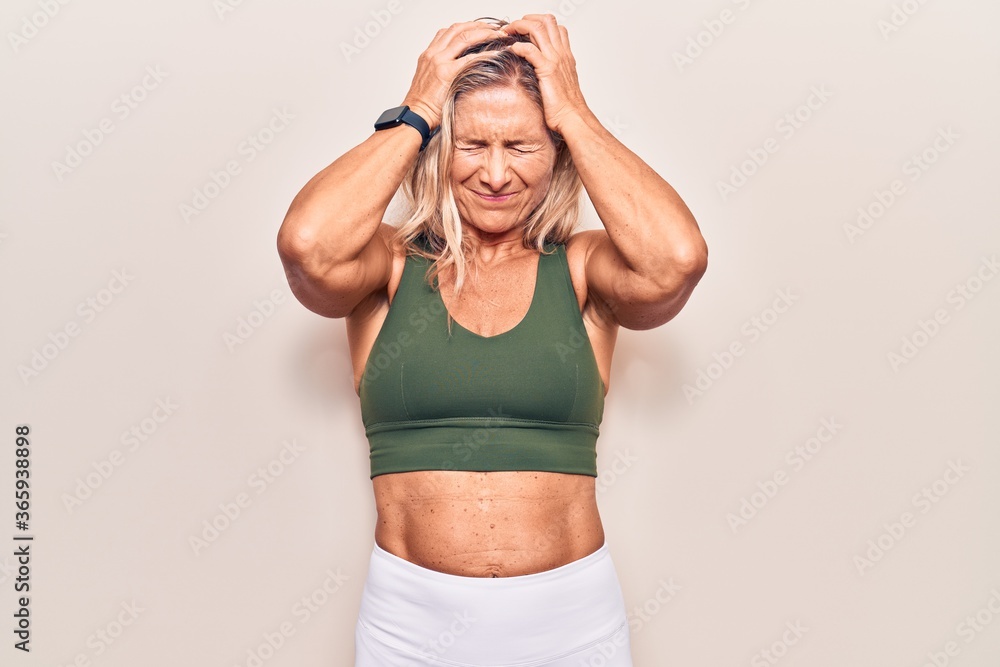Middle age caucasian blonde woman wearing sportswear suffering from headache desperate and stressed because pain and migraine. hands on head. Middle age caucasian blonde woman wearing sportswear suffering from headache desperate and stressed because pain and migraine. hands on head.