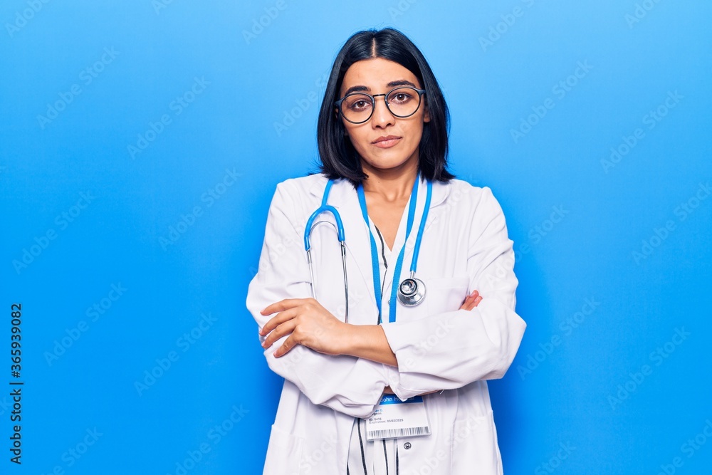 Young beautiful latin woman wearing doctor stethoscope and id card skeptic and nervous, disapproving expression on face with crossed arms. negative person. Young beautiful latin woman wearing doctor stethoscope and id card skeptic and nervous, disapproving expression on face with crossed arms. negative person.