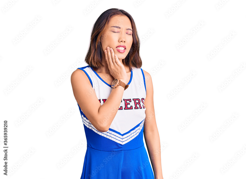Young beautiful chinese girl wearing cheerleader uniform touching mouth with hand with painful expression because of toothache or dental illness on teeth. dentist Young beautiful chinese girl wearing cheerleader uniform touching mouth with hand with painful expression because of toothache or dental illness on teeth. dentist
