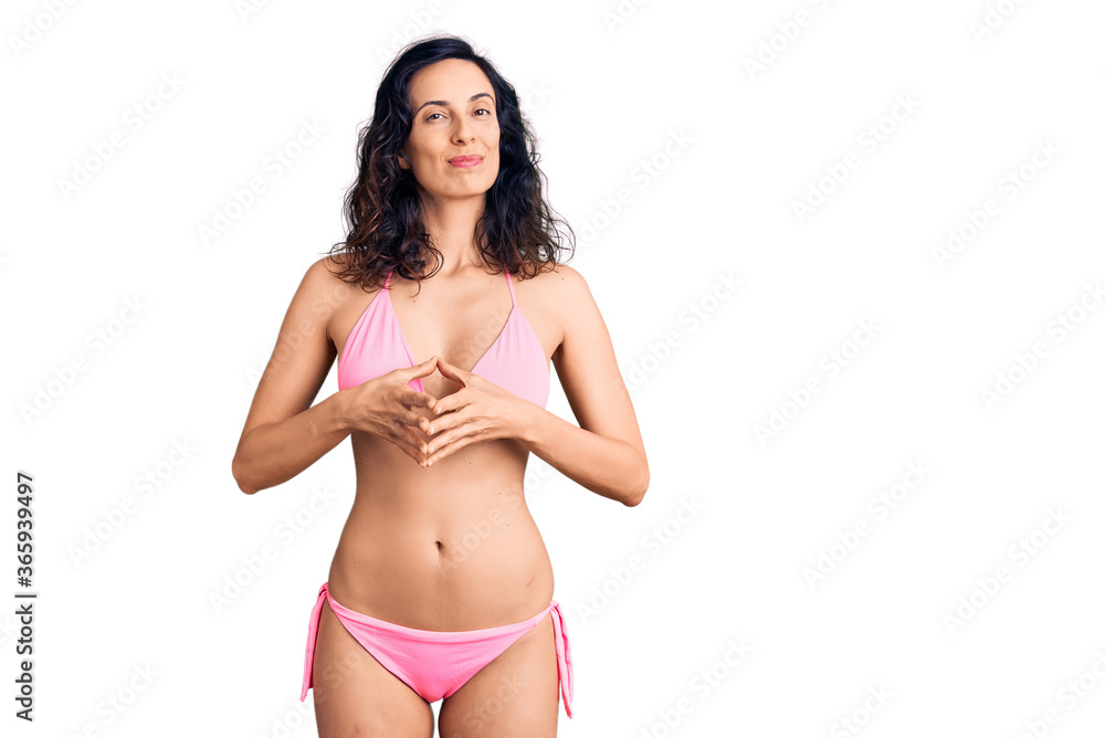 Fototapeta premium Young beautiful hispanic woman wearing bikini hands together and fingers crossed smiling relaxed and cheerful. success and optimistic