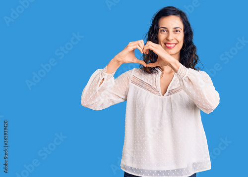 Young beautiful hispanic woman wearing casual clothes smiling in love showing heart symbol and shape with hands. romantic concept.