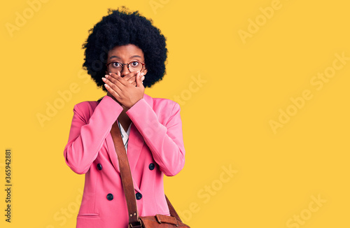 Young african american woman wearing business clothes and leather bag shocked covering mouth with hands for mistake. secret concept.