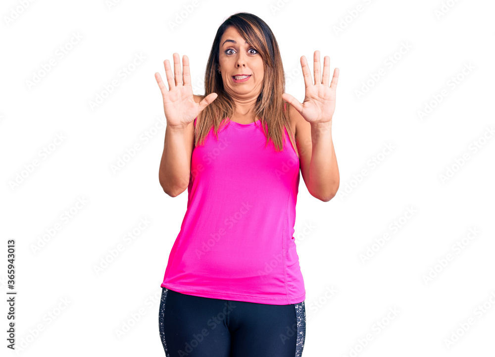Young beautiful woman wearing sportswear afraid and terrified with fear expression stop gesture with hands, shouting in shock. panic concept. Young beautiful woman wearing sportswear afraid and terrified with fear expression stop gesture with hands, shouting in shock. panic concept.